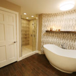 Bathcrashers bath tiled with wood plank floor tile, schluter systems linear drain, and curved mosaic accent wall.